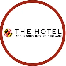 Logo of the hotel at the university of maryland, featuring a red circular border with "the hotel" in bold, black letters and a stylized image of a maryland flag and a terrapin on the left.